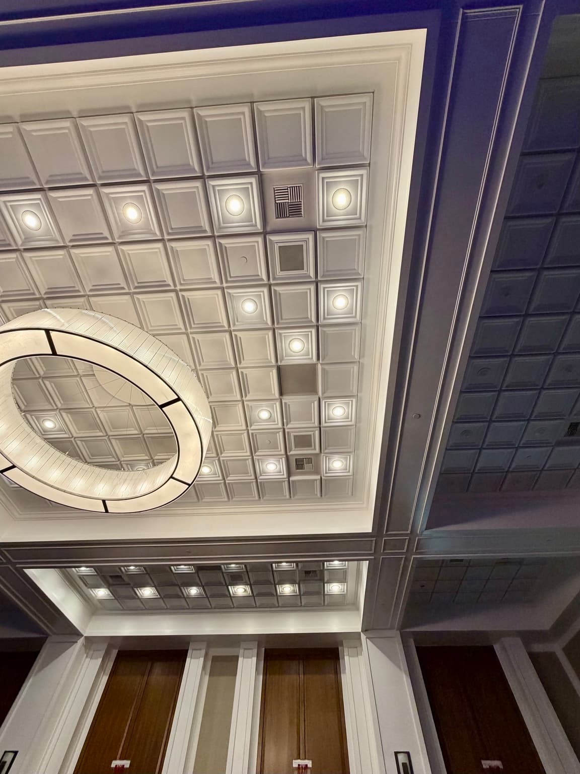 Qwel recessed tiles around the central chandelier and adjacent ceiling bays